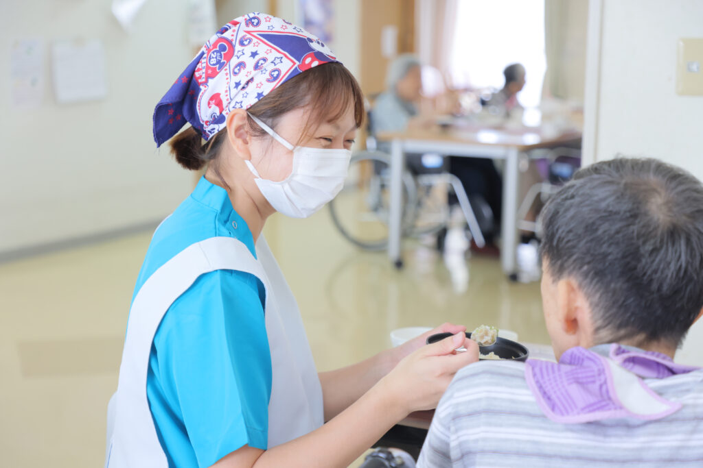 介護職員が入居者にケアを提供する風景。マスク着用で感染対策を実施。